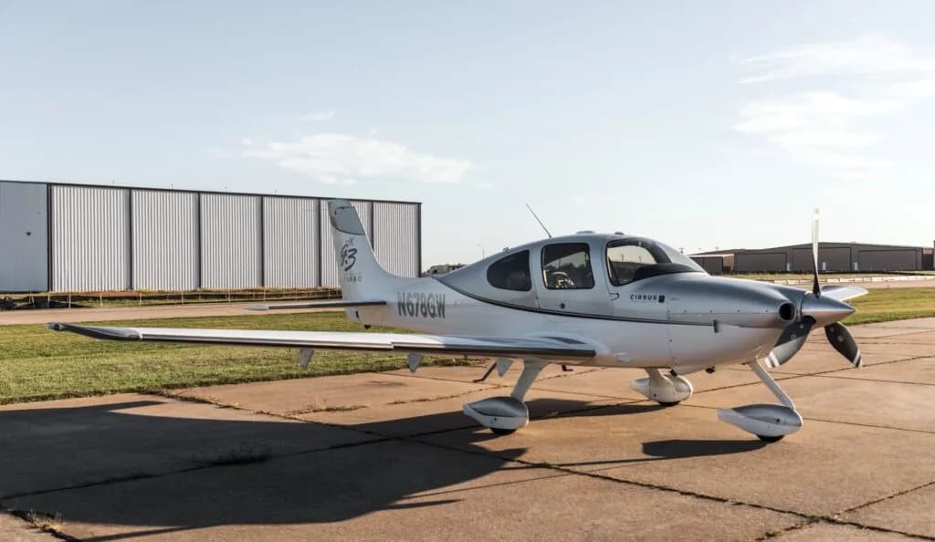 A front quarter view of a silver and white Cirrus SR22 G3 Turbo aircraft (N678GW) parked on an airfield.