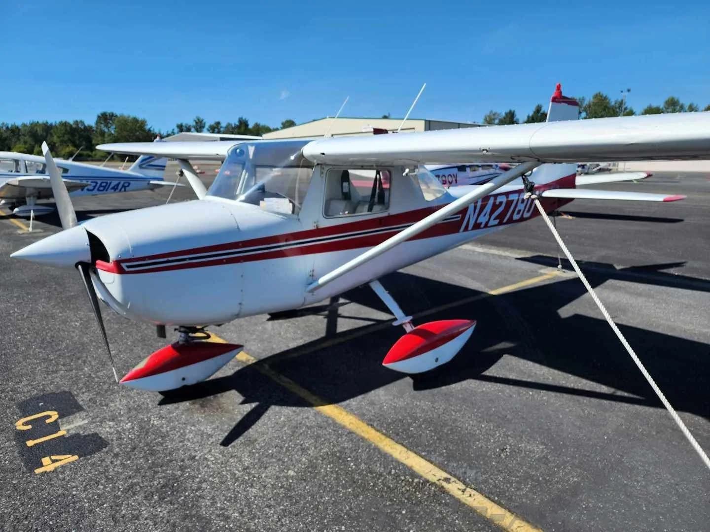 A white and red Cessna 150 aircraft with registration N4278U parked on an airfield, viewed from the front-right.