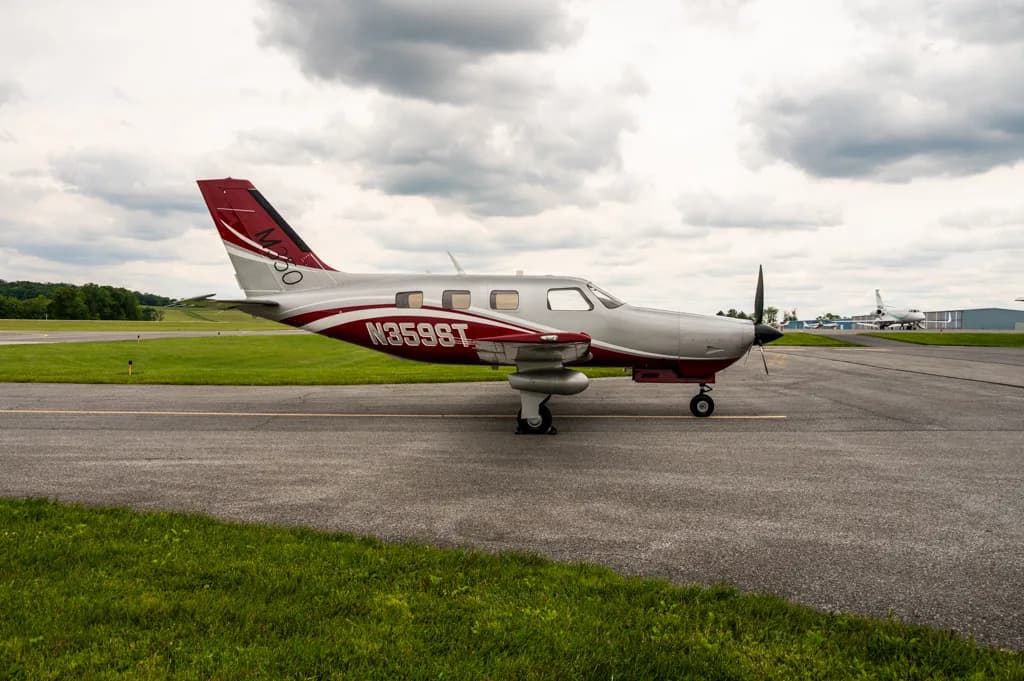 A side view of a silver and red single-engine turboprop aircraft with tail number N3598T parked on an airfield.