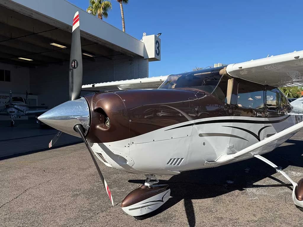 A close-up view of the propeller and nose of the brown and white Cessna 182 Skylane N54ZA.
