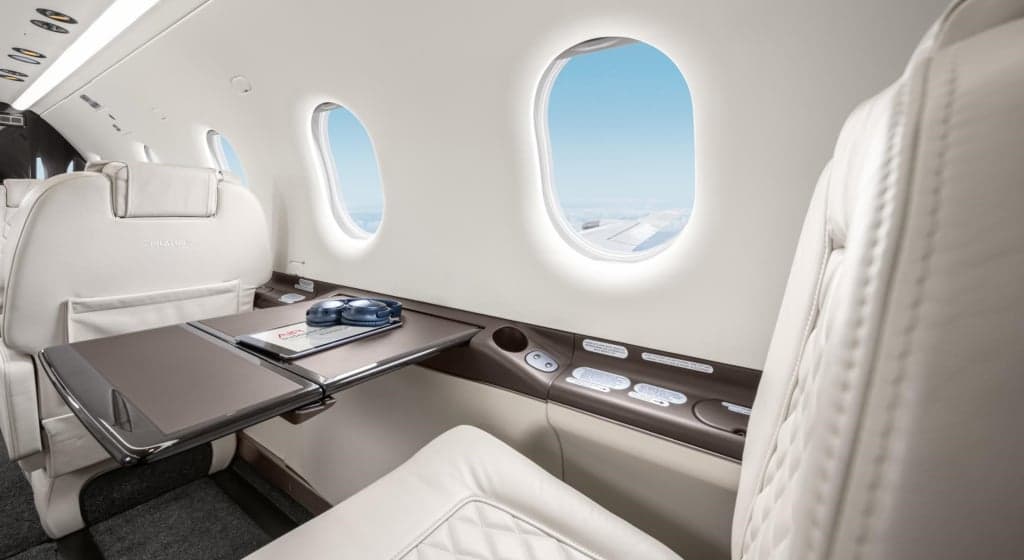 Interior view of the aircraft cabin with white leather seats and a table.