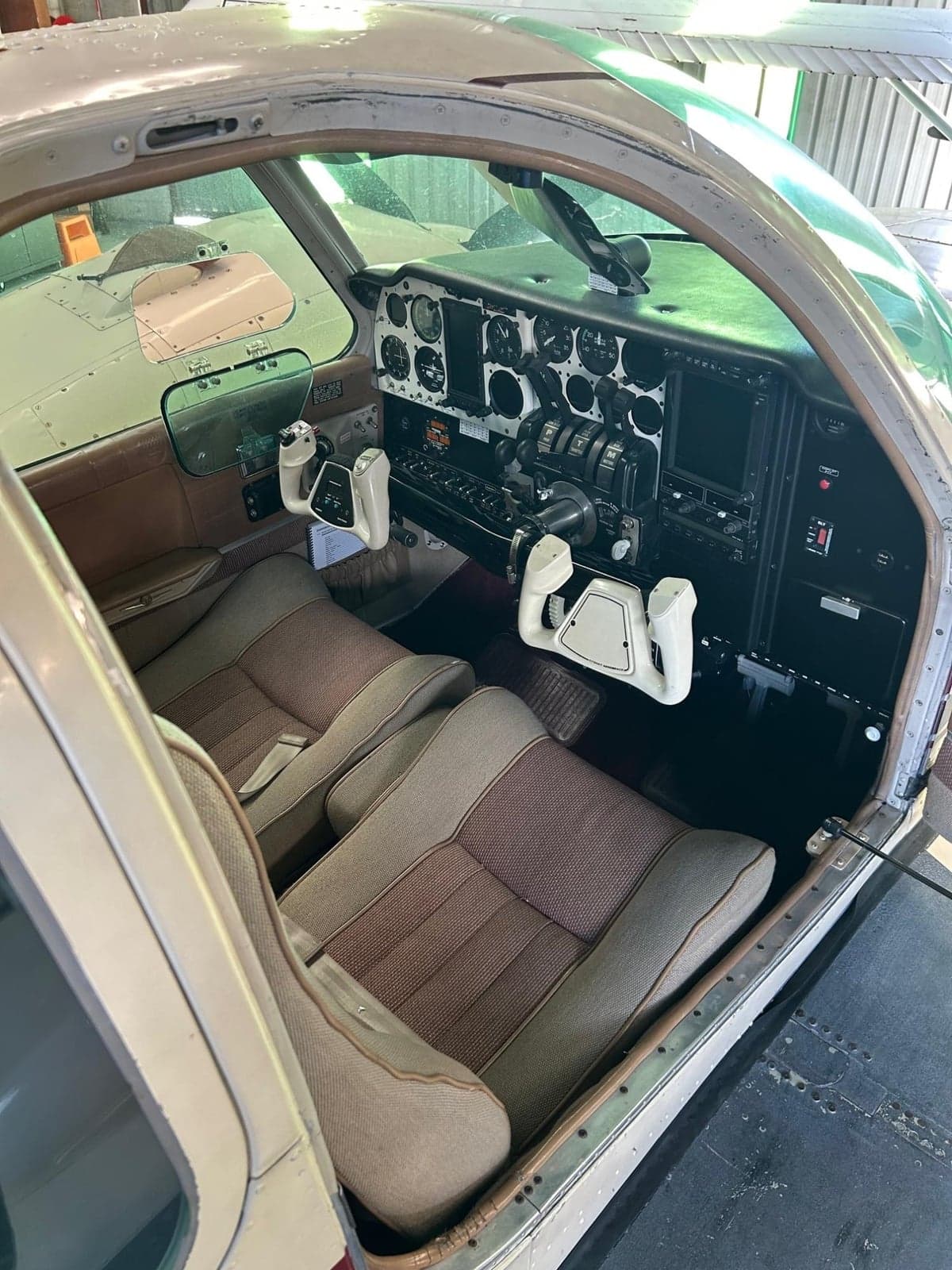 The cockpit of an aircraft with a full instrument panel, dual yokes, and two front seats.