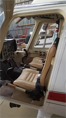 Cockpit view of the helicopter with beige seats and instrument panel.