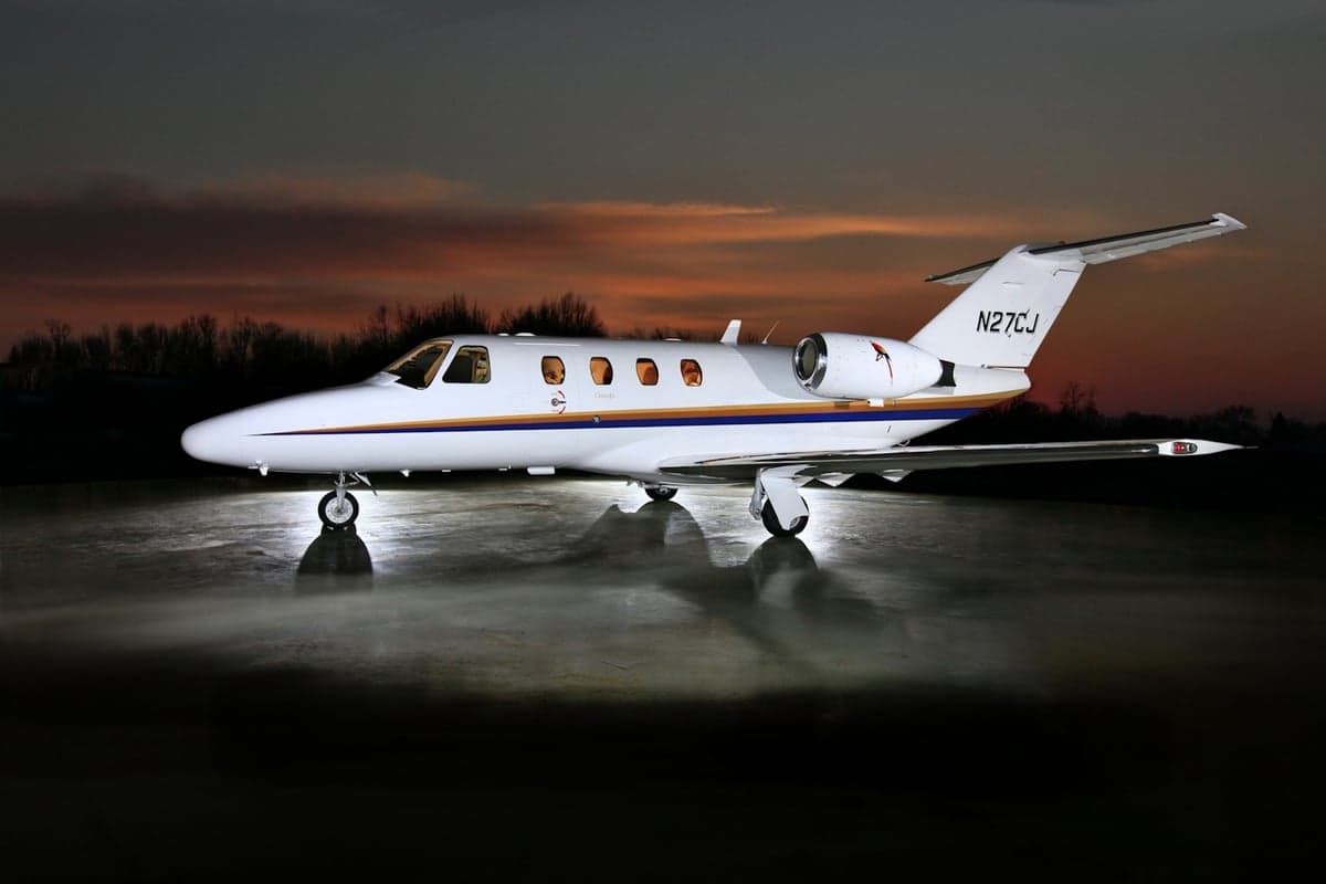 A CitationJet N27CJ is parked on the tarmac at dusk.