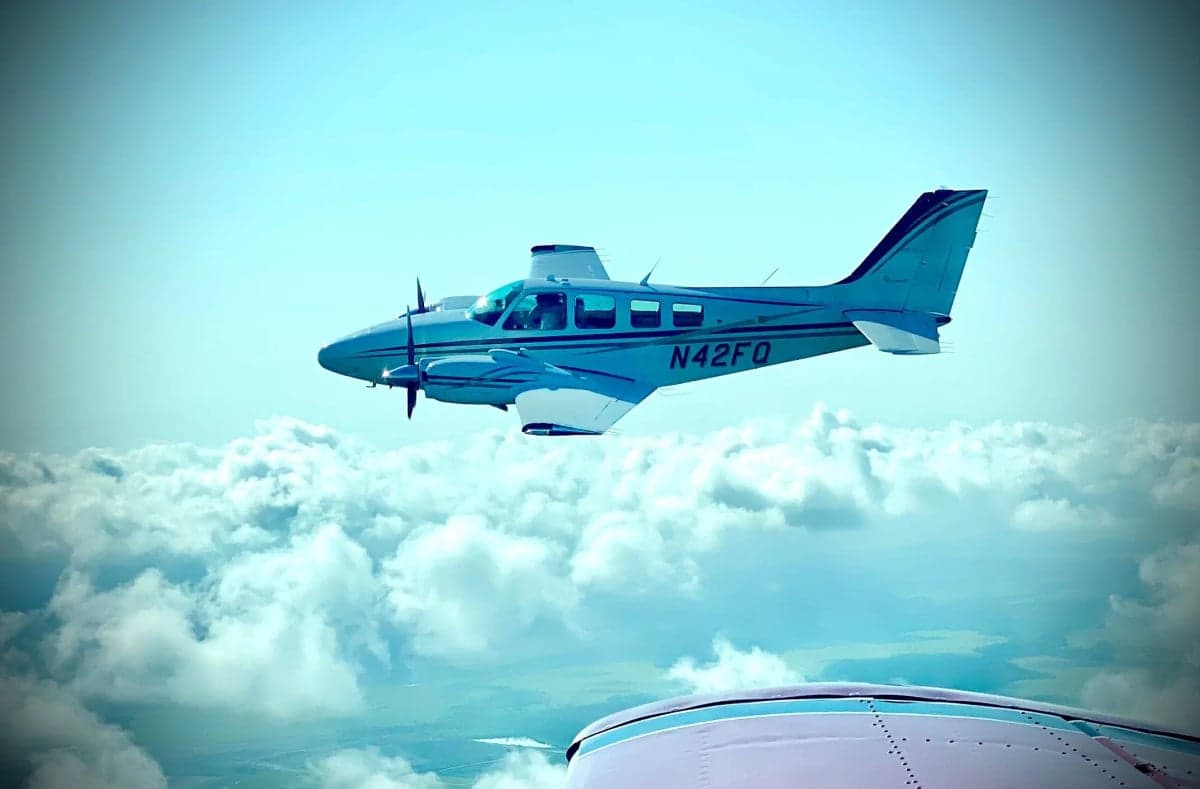 Beechcraft Baron N42FQ in flight above the clouds.