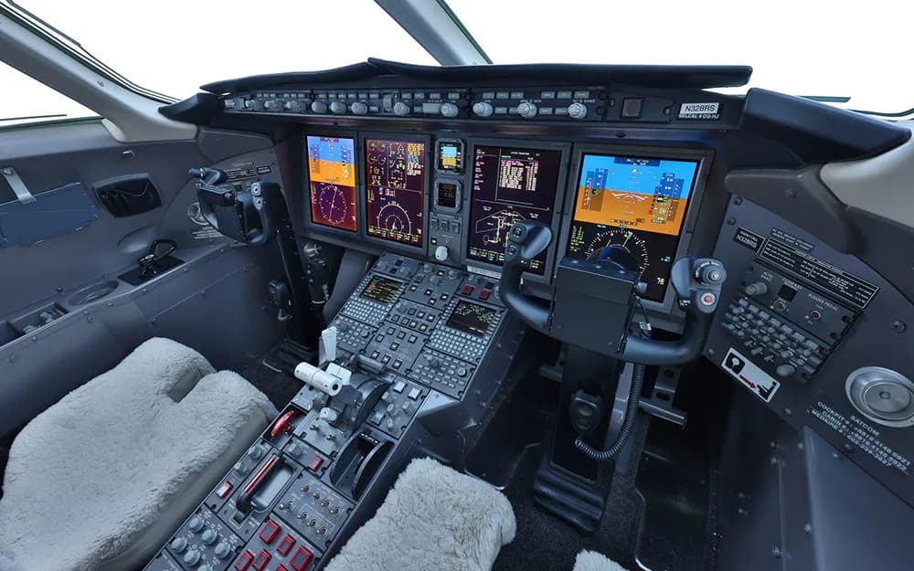 An angled view of the aircraft cockpit, showing the pilot's control yoke, instrument panel, and digital screens.