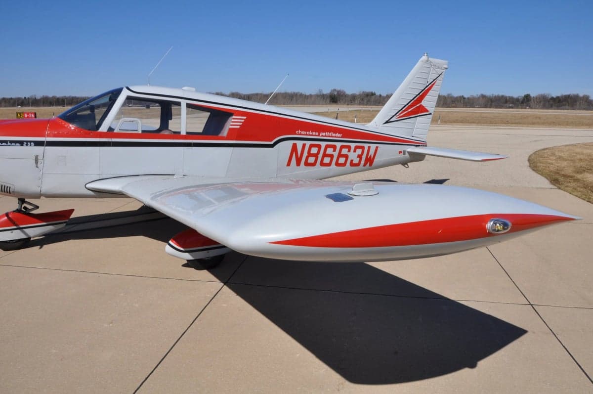 Close-up of the wing and fuselage of a Cherokee 180 aircraft.