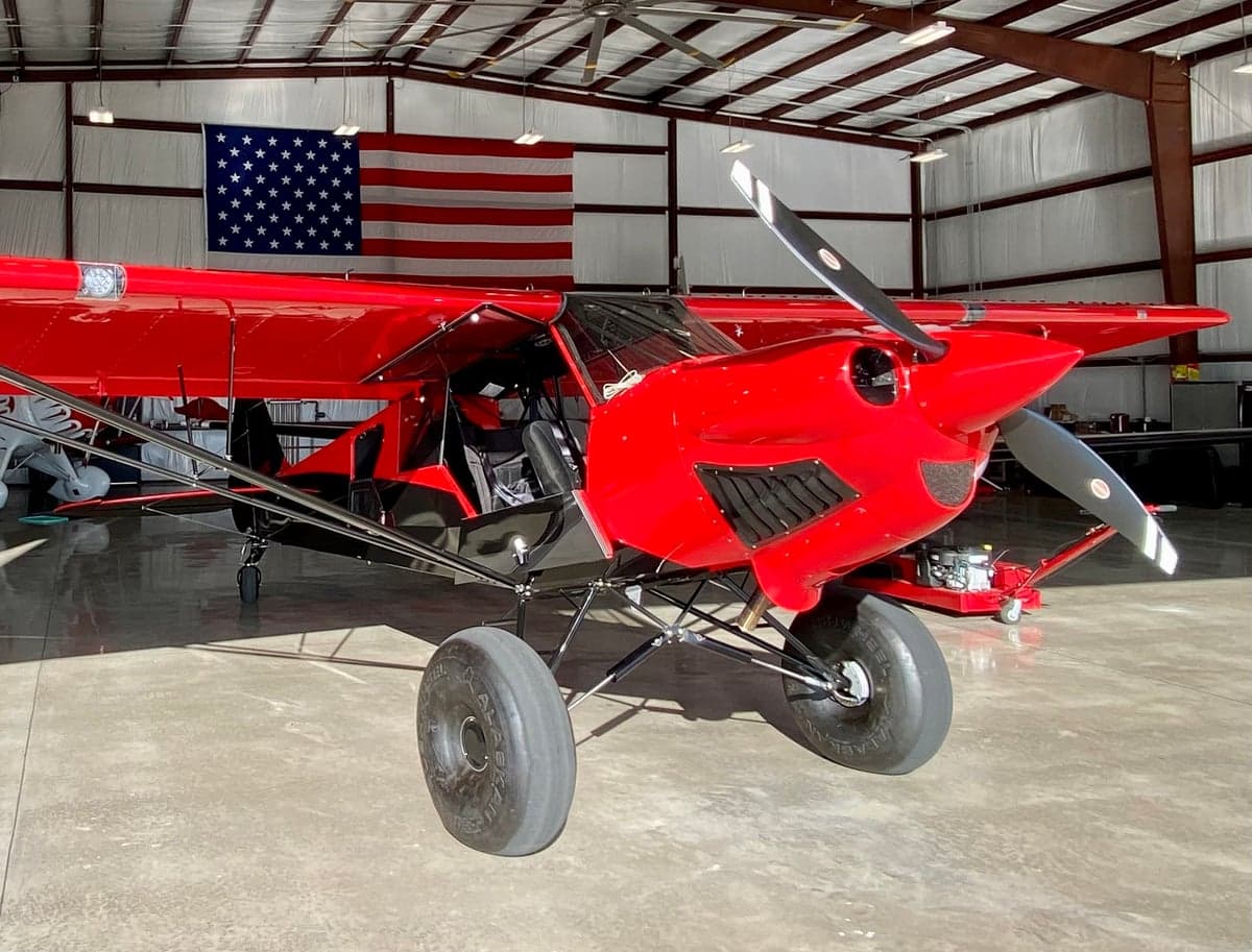 Front view of the red and black N83ZC aircraft in a hangar with an American flag in the background.