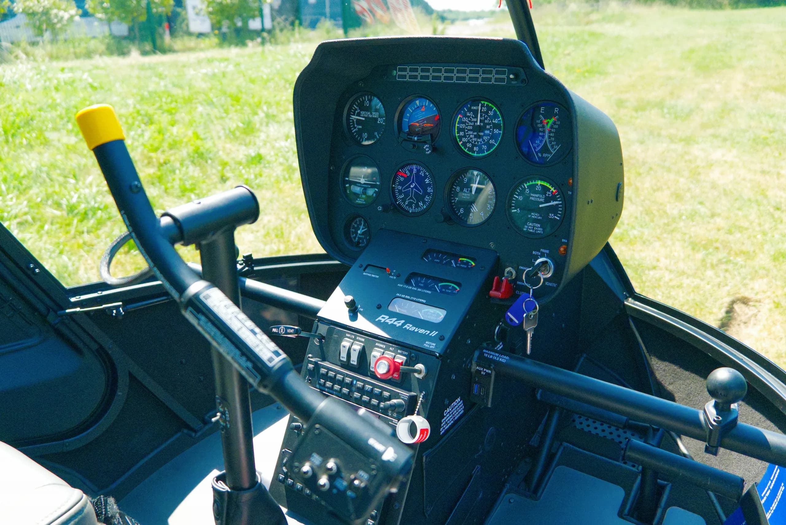 The cockpit of a Robinson R44 Raven II helicopter shows the instrument panel and controls.