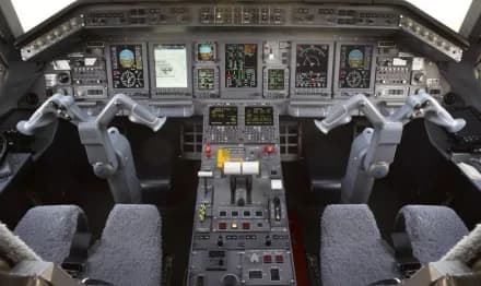 The modern cockpit of an aircraft, featuring multiple digital displays and a complex control panel.