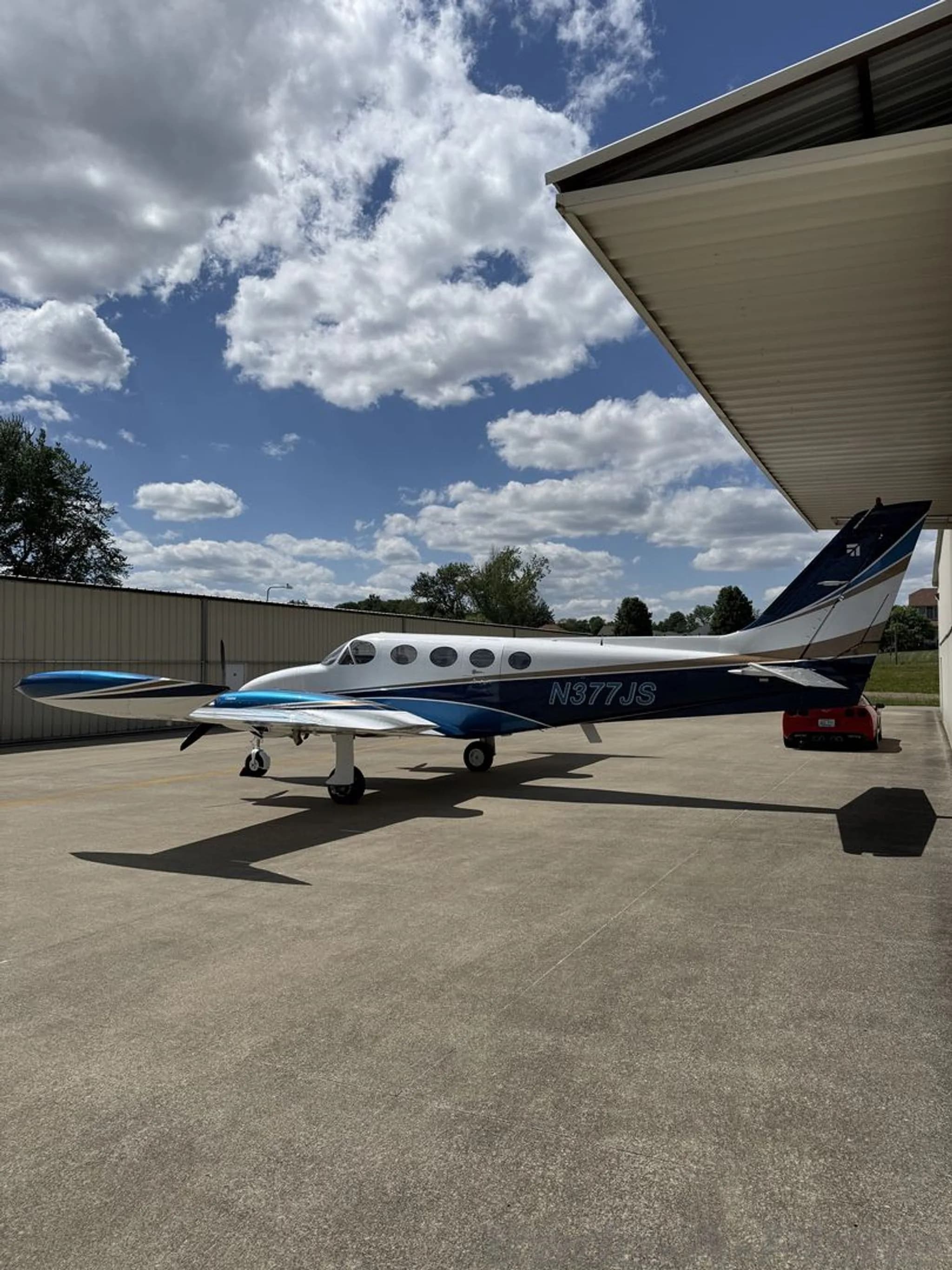 A side view of the N377JS Cessna 414 twin-engine aircraft with its white, blue, and gold paint scheme.