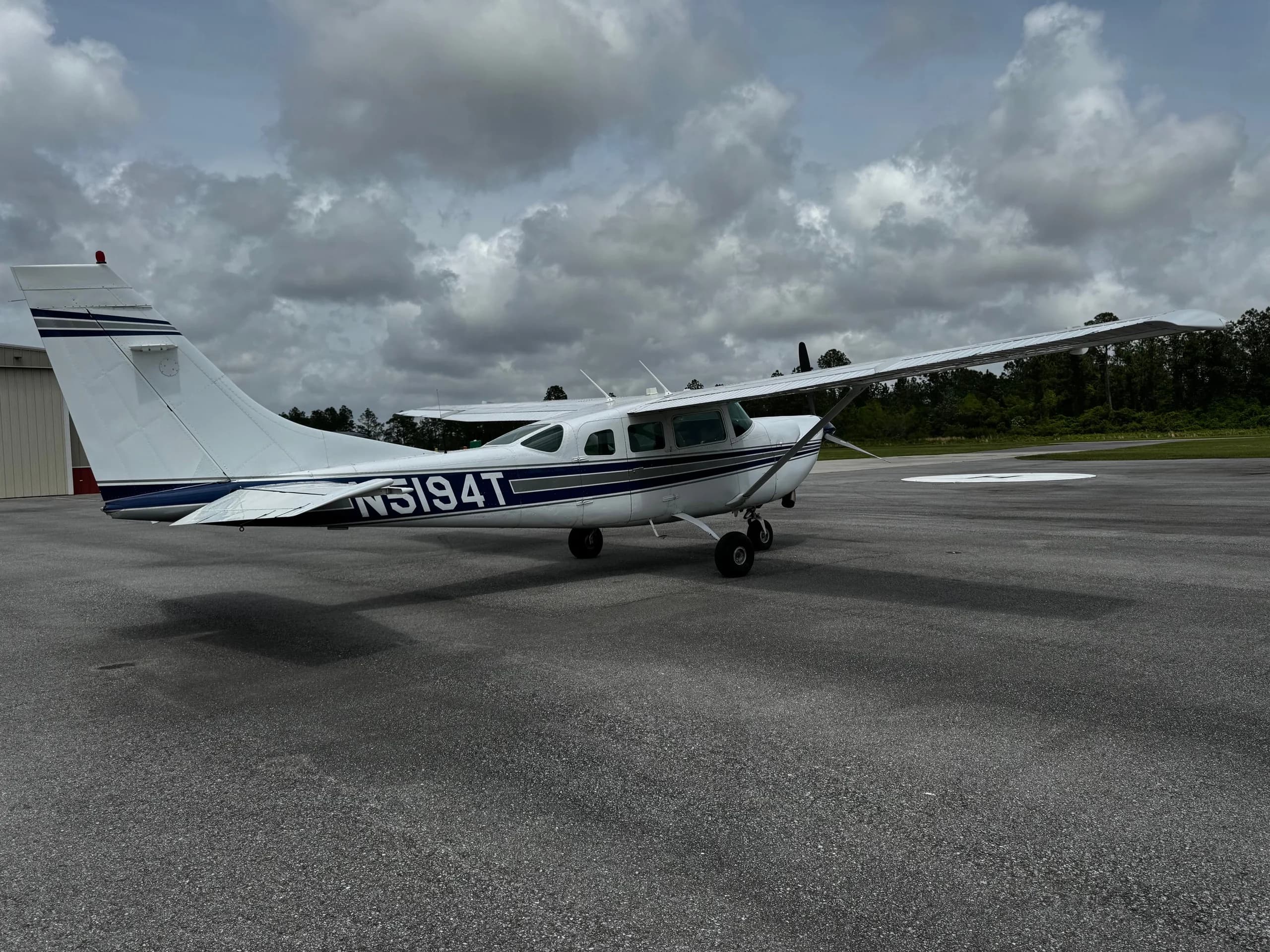 Side view of a white and blue Cessna 206 Turbo Stationair with tail number N5194T on the tarmac.