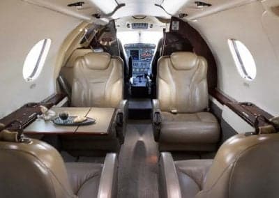The Citation CJ3+ cabin features forward-facing leather seats and a small table with refreshments.