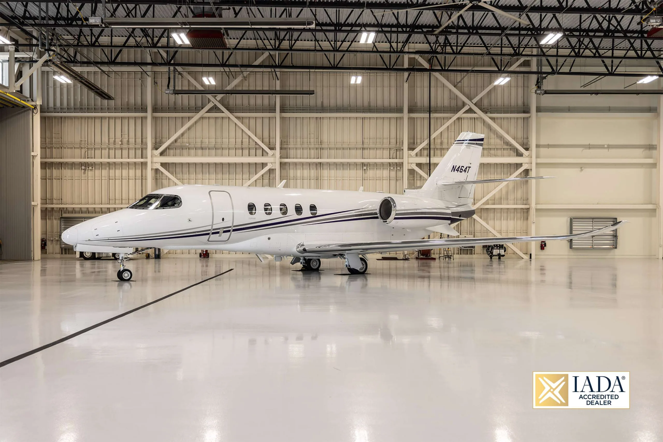 The N464T business jet is parked inside a brightly lit hangar with a white floor.