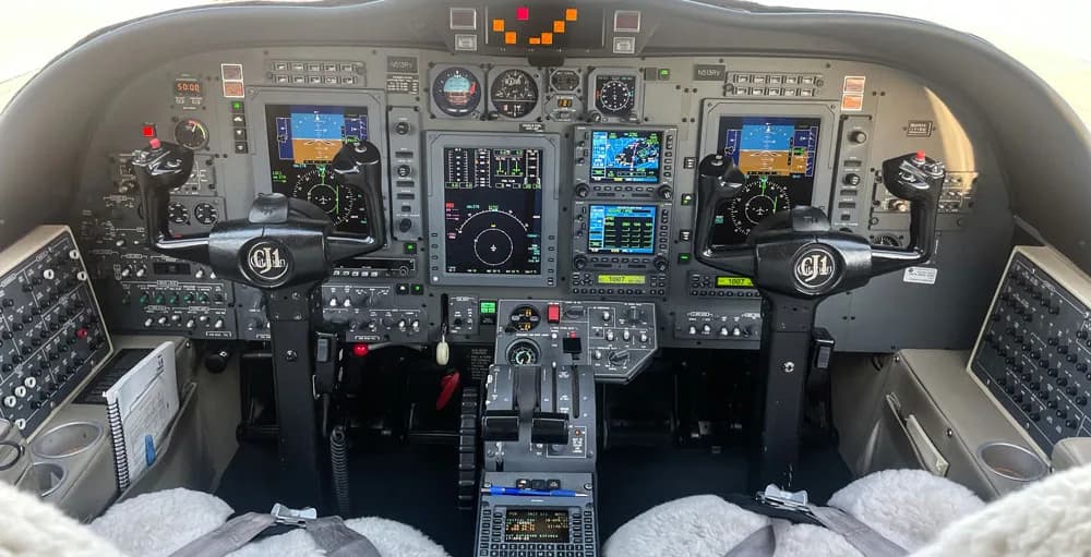 The cockpit of a Cessna CitationJet, featuring a modern glass panel display and dual yokes.