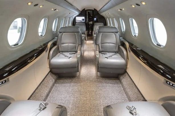 The interior of the jet features gray leather seats and a gray carpet.