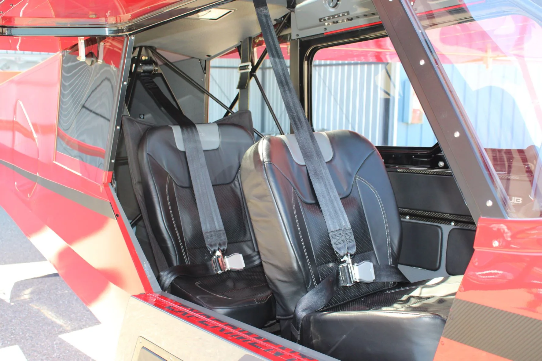 Interior view of the NX Cub aircraft showing the black leather seats with seatbelts.