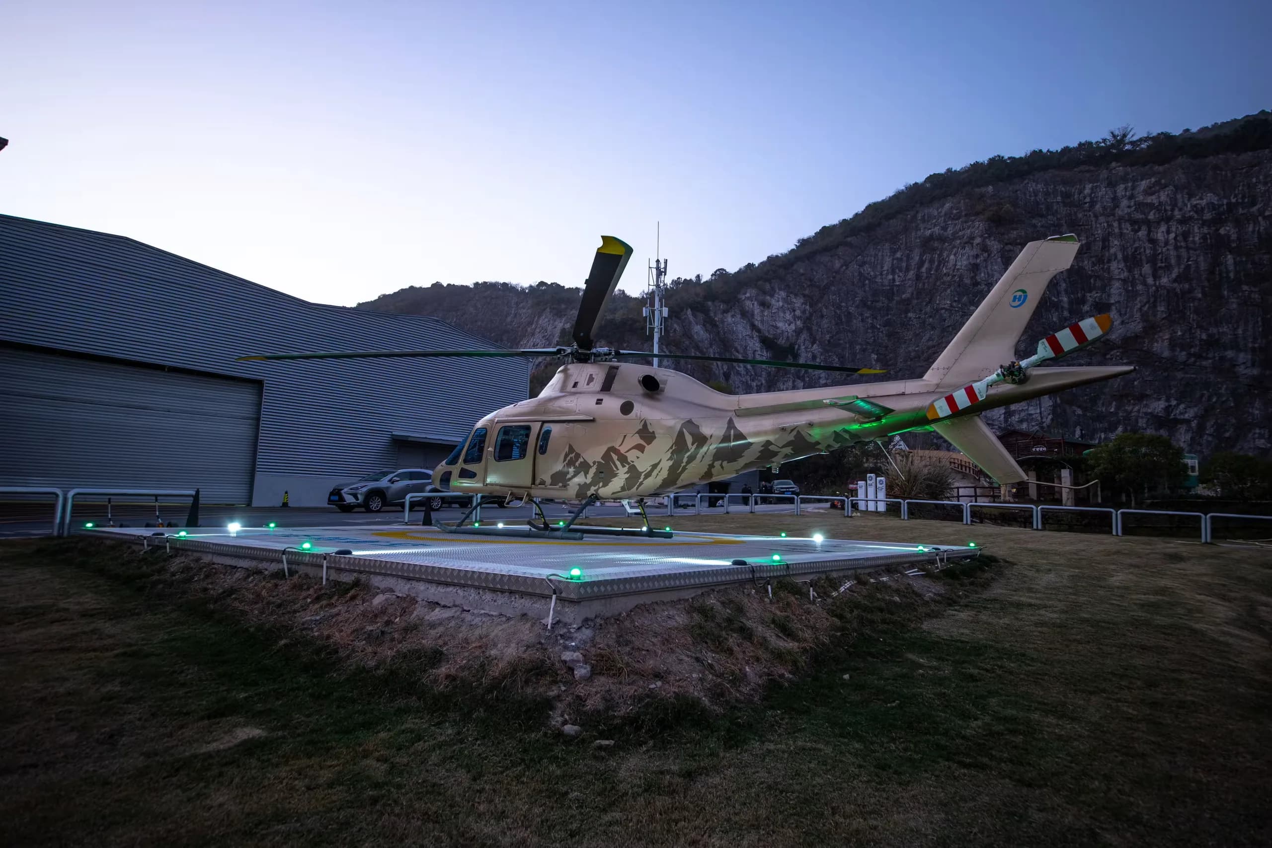 A B-704A helicopter is parked on a helipad near a building.