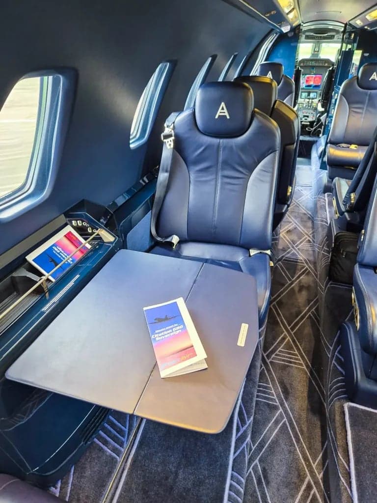 View of the aircraft's interior cabin with blue leather seats and a table.