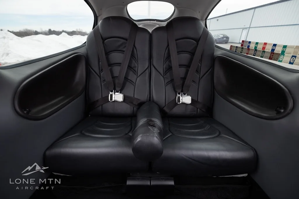 View of the black leather rear seats with harnesses inside the Cirrus SR22 cabin.