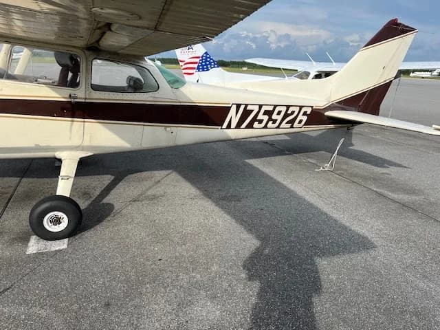 Side view of the brown and white Cessna N75926 aircraft parked on an asphalt tarmac.