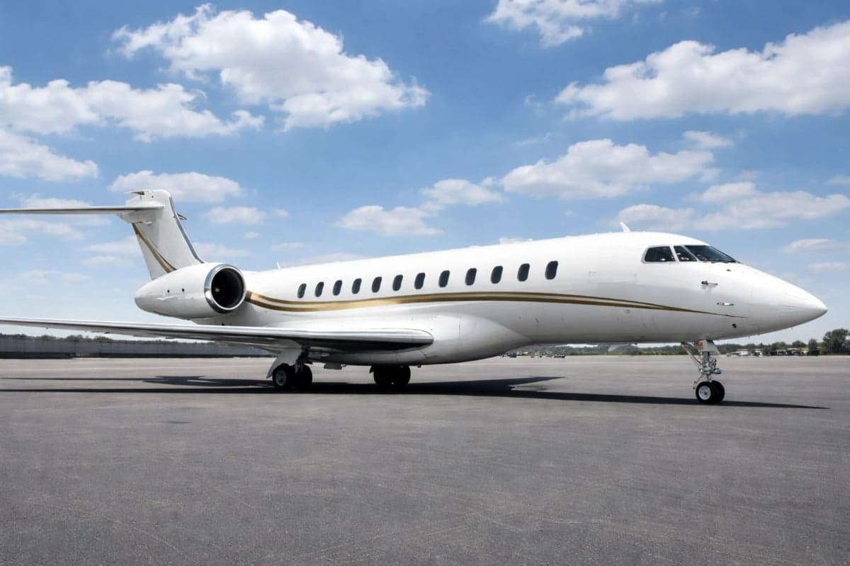 Side view of a white aircraft with gold stripes on a sunny day.