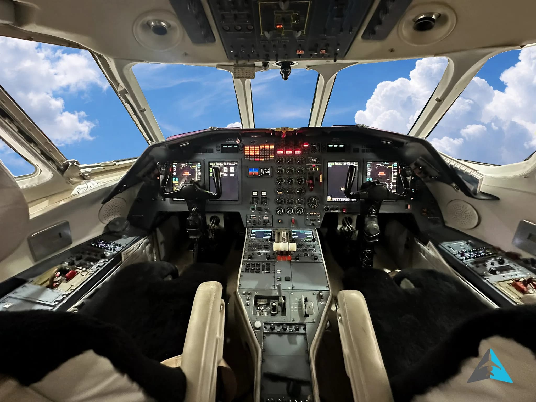 A wide view of the modern cockpit of a business jet with multiple screens and controls.