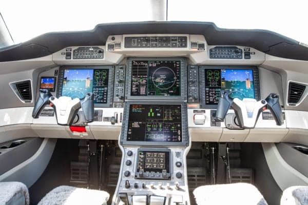 View of the aircraft cockpit with multiple display screens and controls.