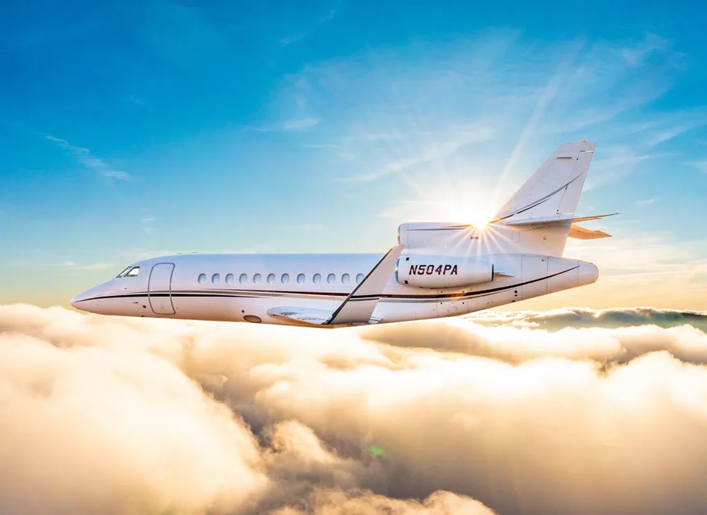 A Dassault Falcon 900EX business jet, registration N504PA, flying above clouds with the sun shining.