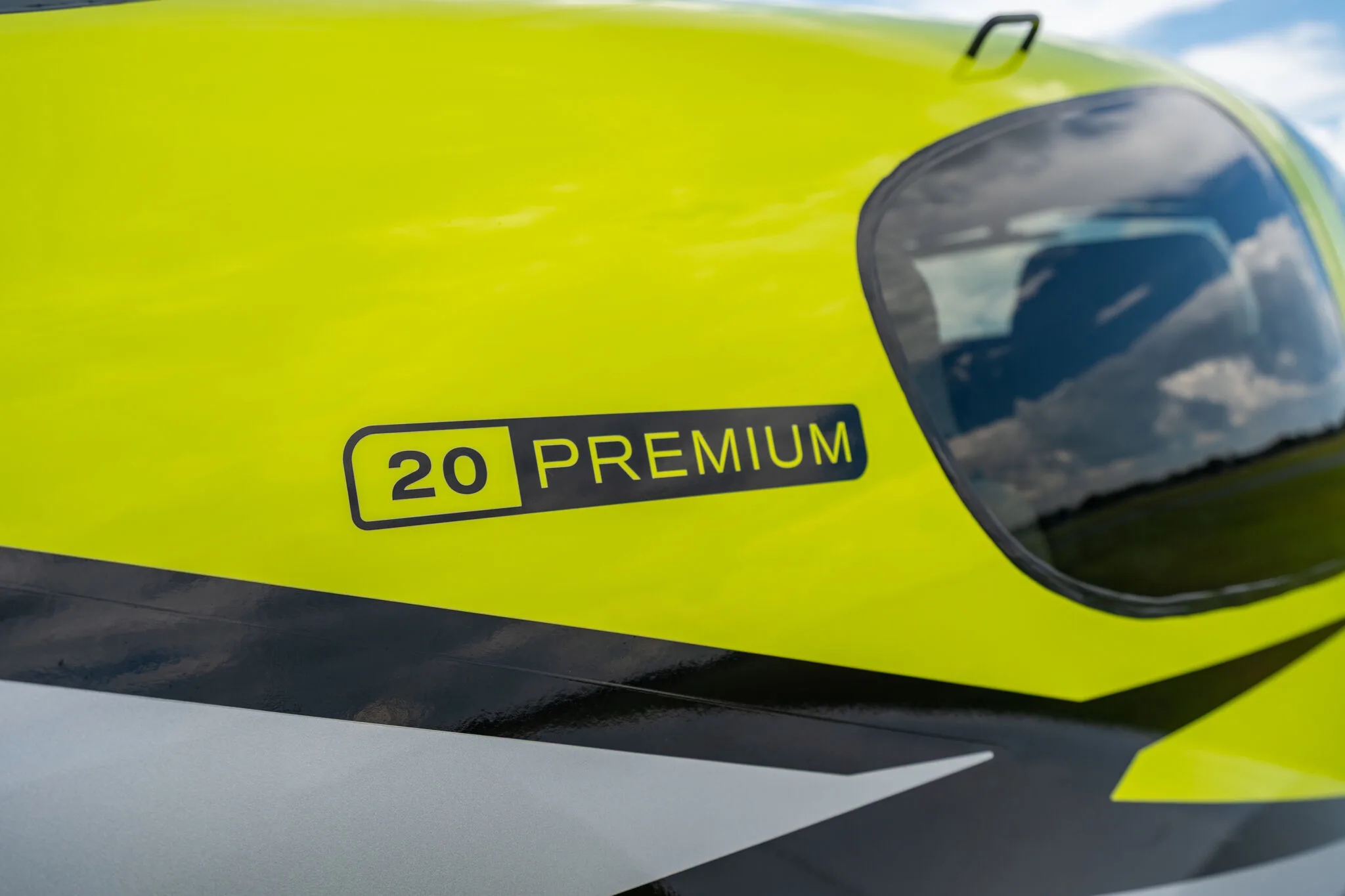 Close-up of the "20 PREMIUM" decal on the lime green fuselage of a Cirrus SR20 aircraft.