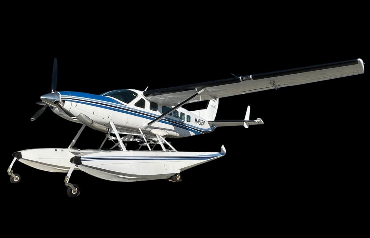 A white and blue Cessna Caravan on floats, with registration N518KM, isolated against a black background.