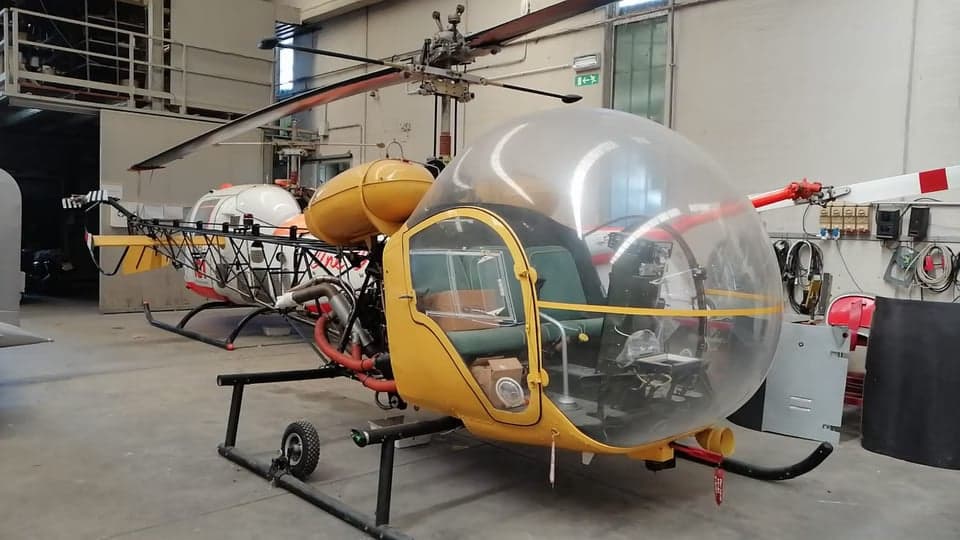 Side view of a yellow and white helicopter in a hangar.