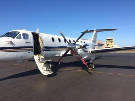 A King Air aircraft is parked on the tarmac with the airstair door open.