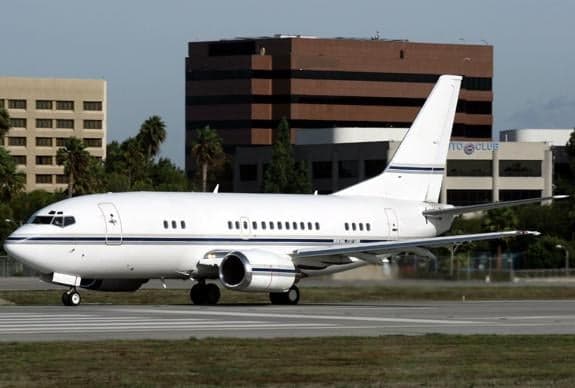 A white Boeing 737 on the tarmac at an airport.