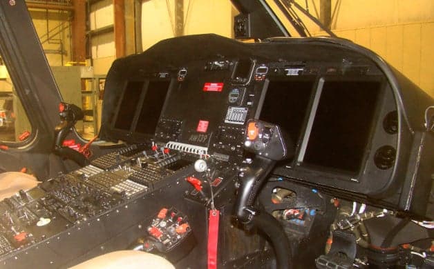 The cockpit of an AW139 helicopter features a black instrument panel and controls.
