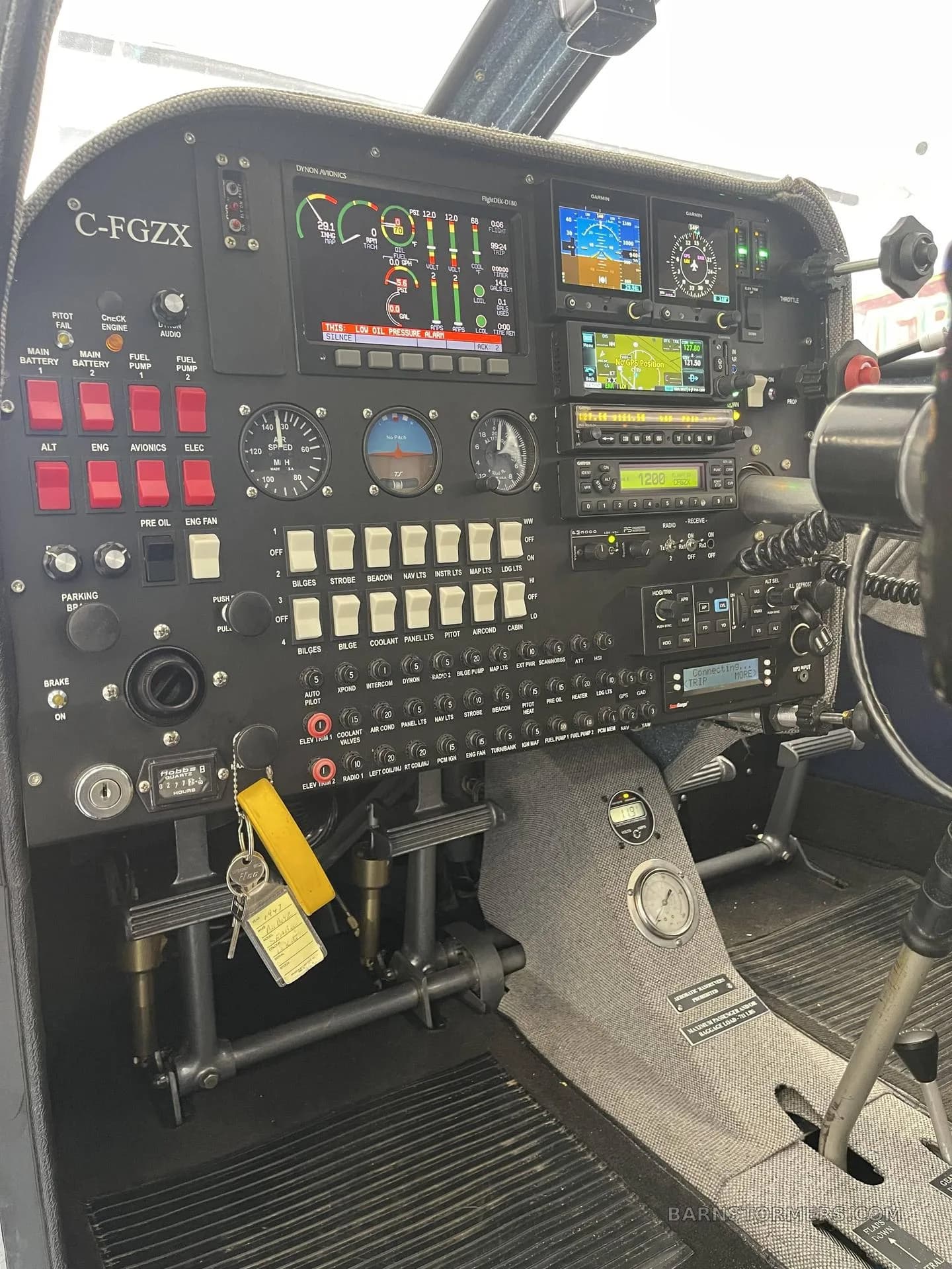 A detailed view of an aircraft cockpit, showing the instrument panel with digital displays, switches, and rudder pedals.