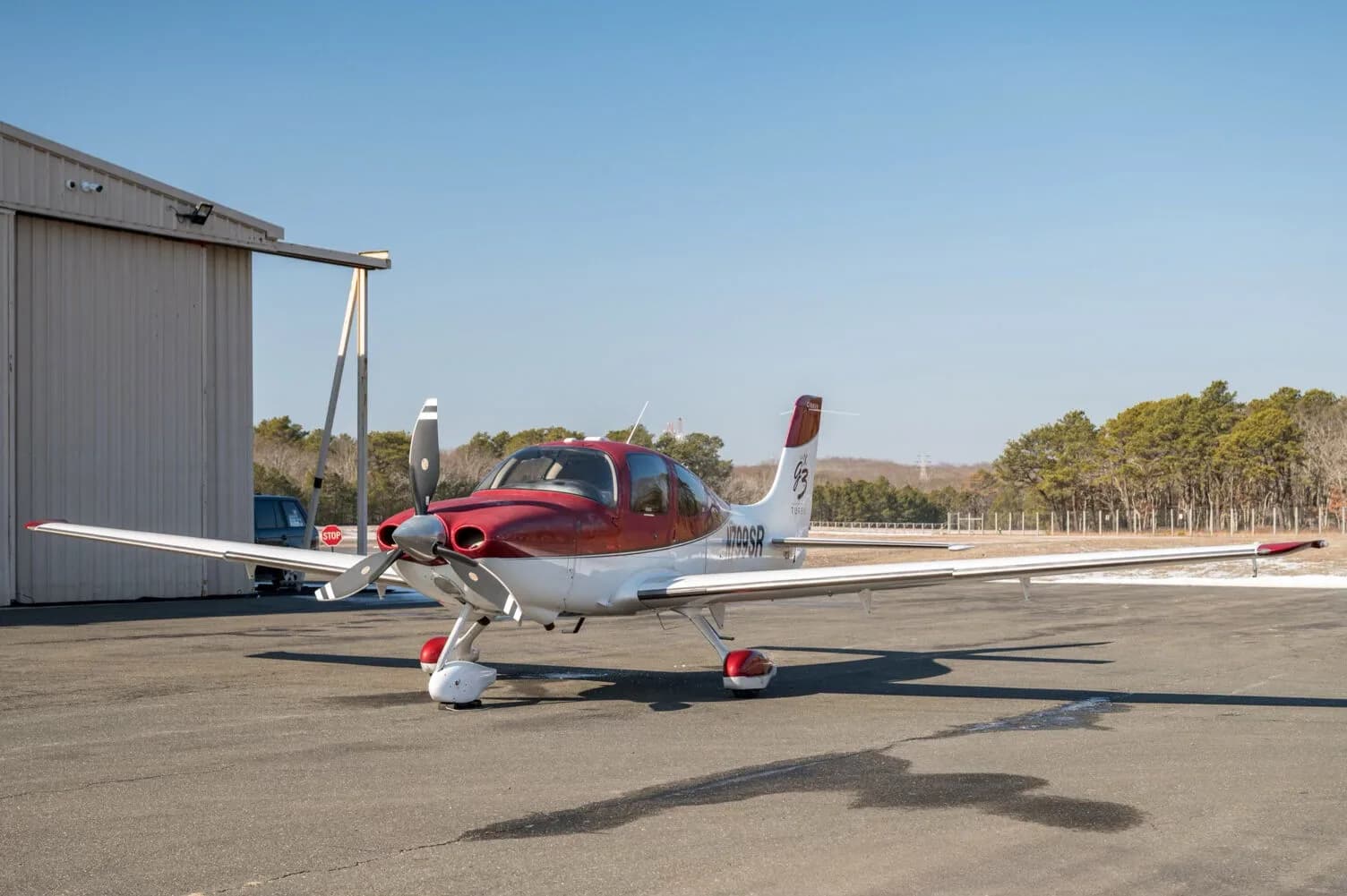 A front-side view of a red and white Cirrus SR22T aircraft, N799SR, parked on an tarmac.
