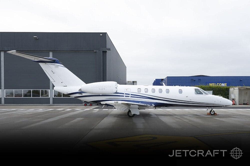 A CJ4 aircraft parked on the tarmac in front of a hangar.