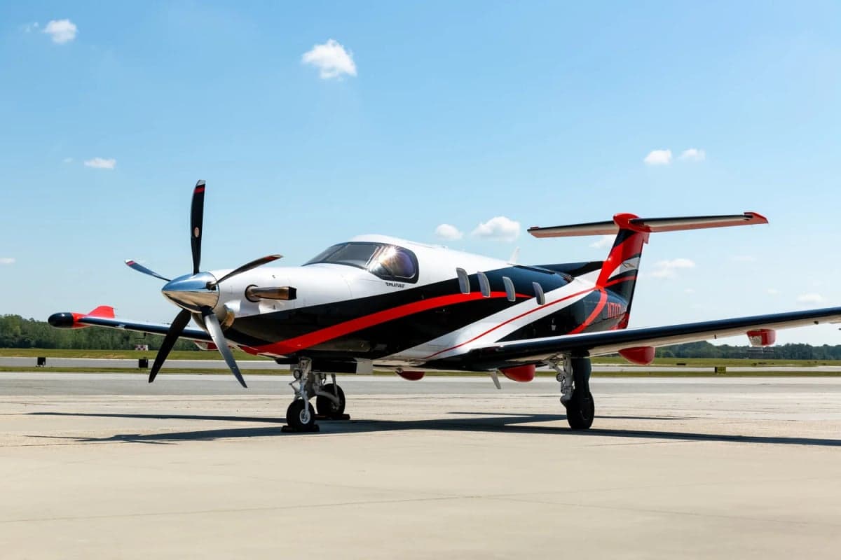 Pilatus PC-12 on the tarmac with a black, white, and red paint scheme.