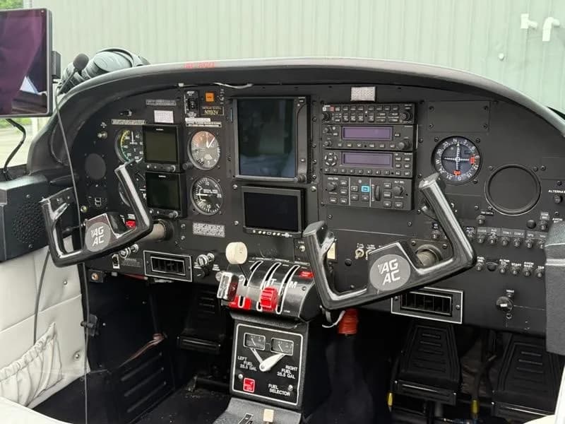 The cockpit of a single-engine aircraft, showing the instrument panel, yokes, and throttle quadrant.
