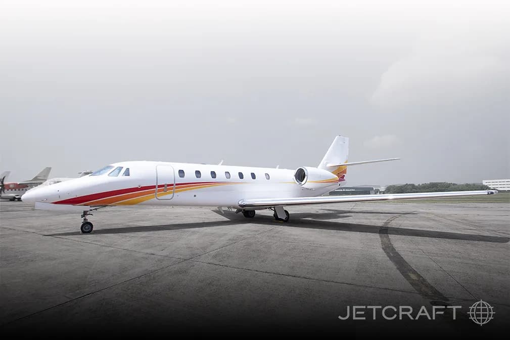 A white jet with red and orange stripes parked on the tarmac.
