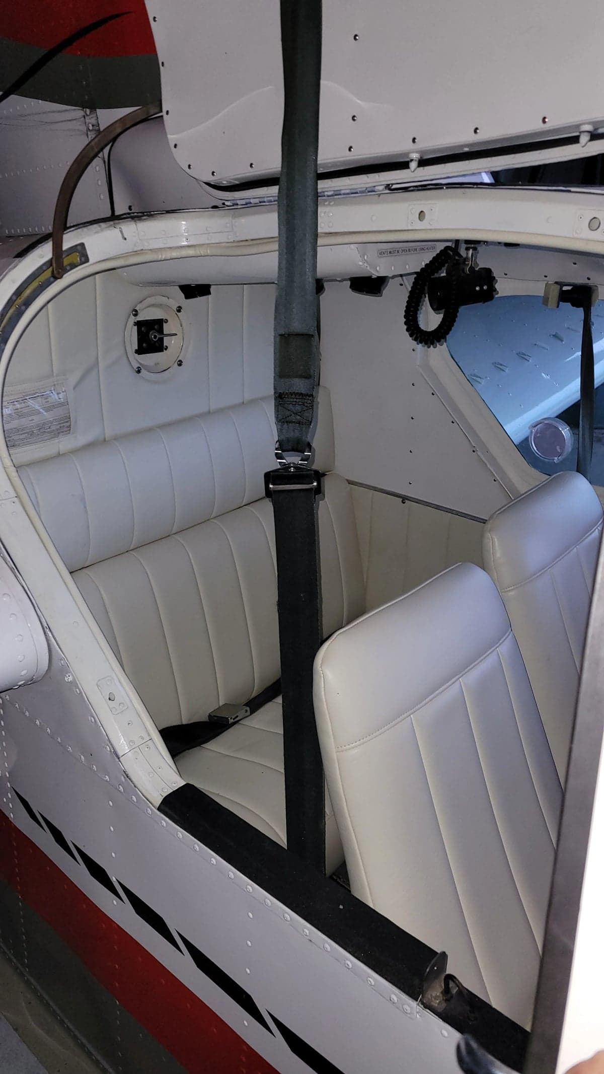 The interior of the aircraft features white seats and a black seatbelt.