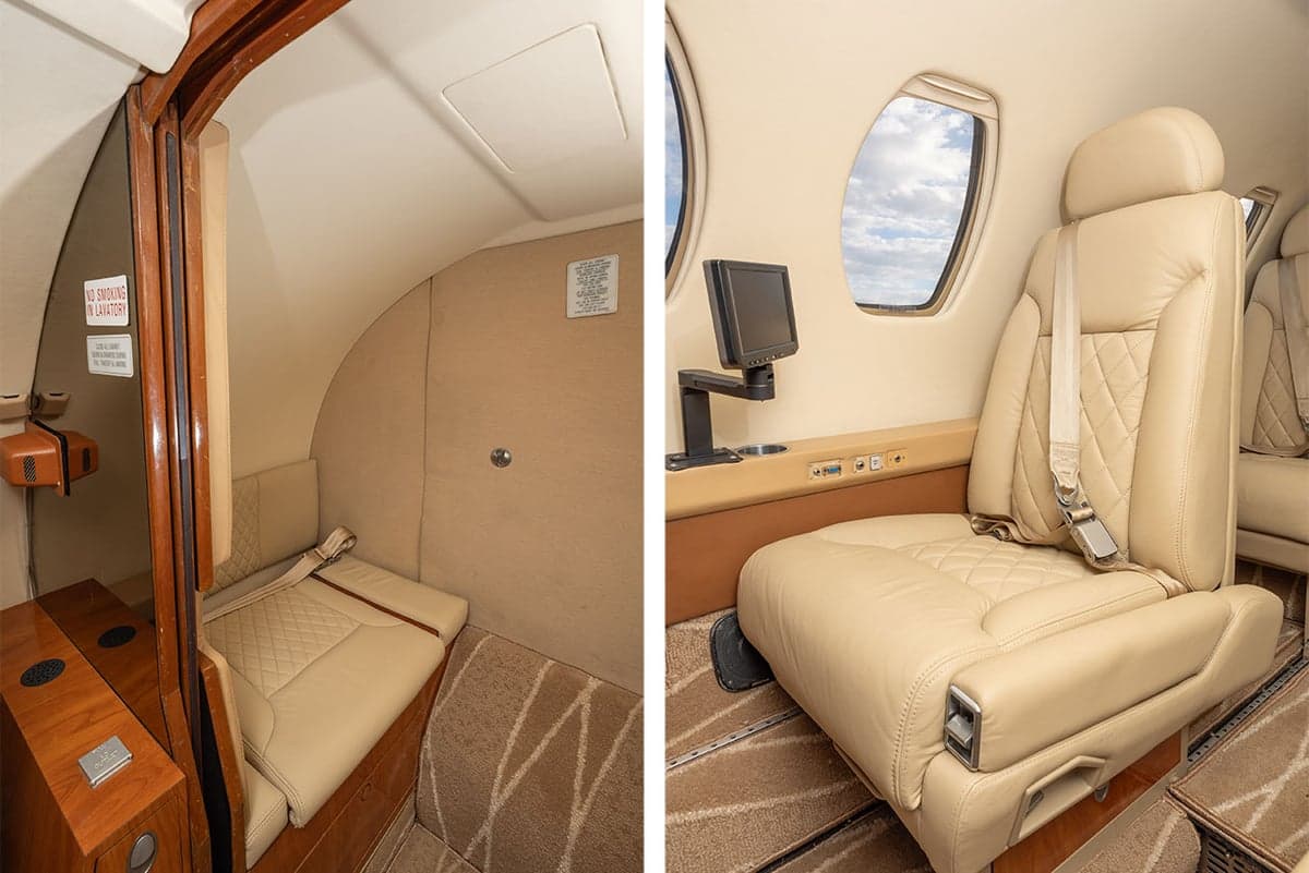 Interior view of the aircraft cabin with tan leather seats and a small entertainment screen.