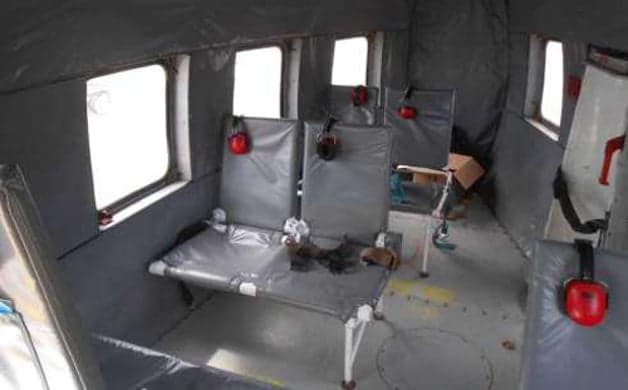 Interior view of the helicopter cabin with passenger seats and headsets.
