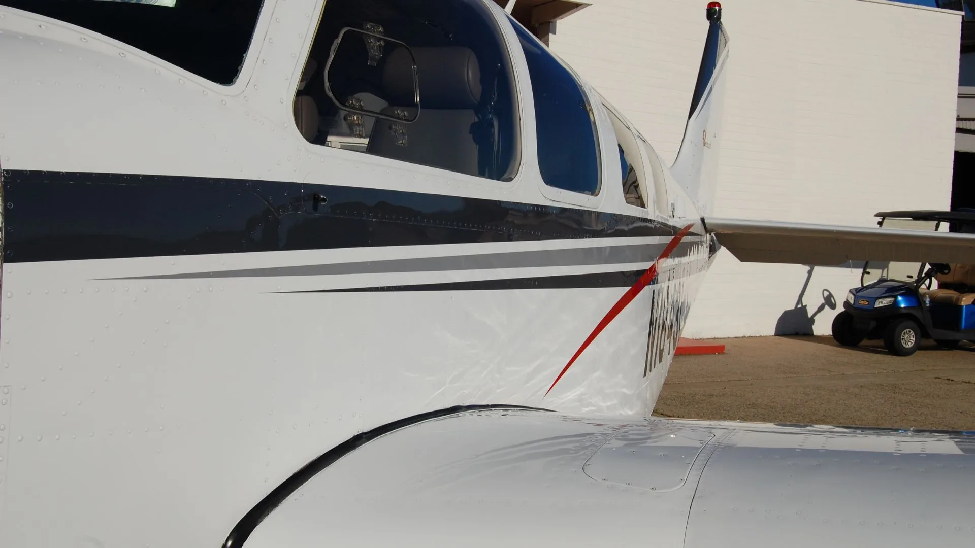 Close-up of the side of a Beechcraft Bonanza, showing the paint scheme and registration number.