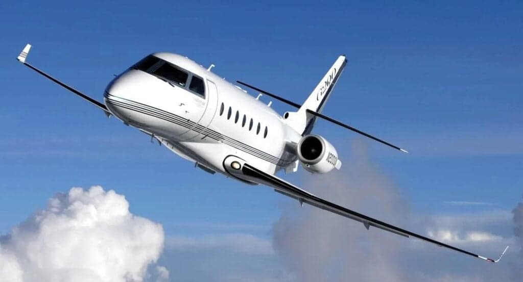 A Cessna Citation CJ3+ in flight against a blue sky with clouds.
