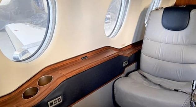 View of the aircraft cabin with leather seats and wood trim.