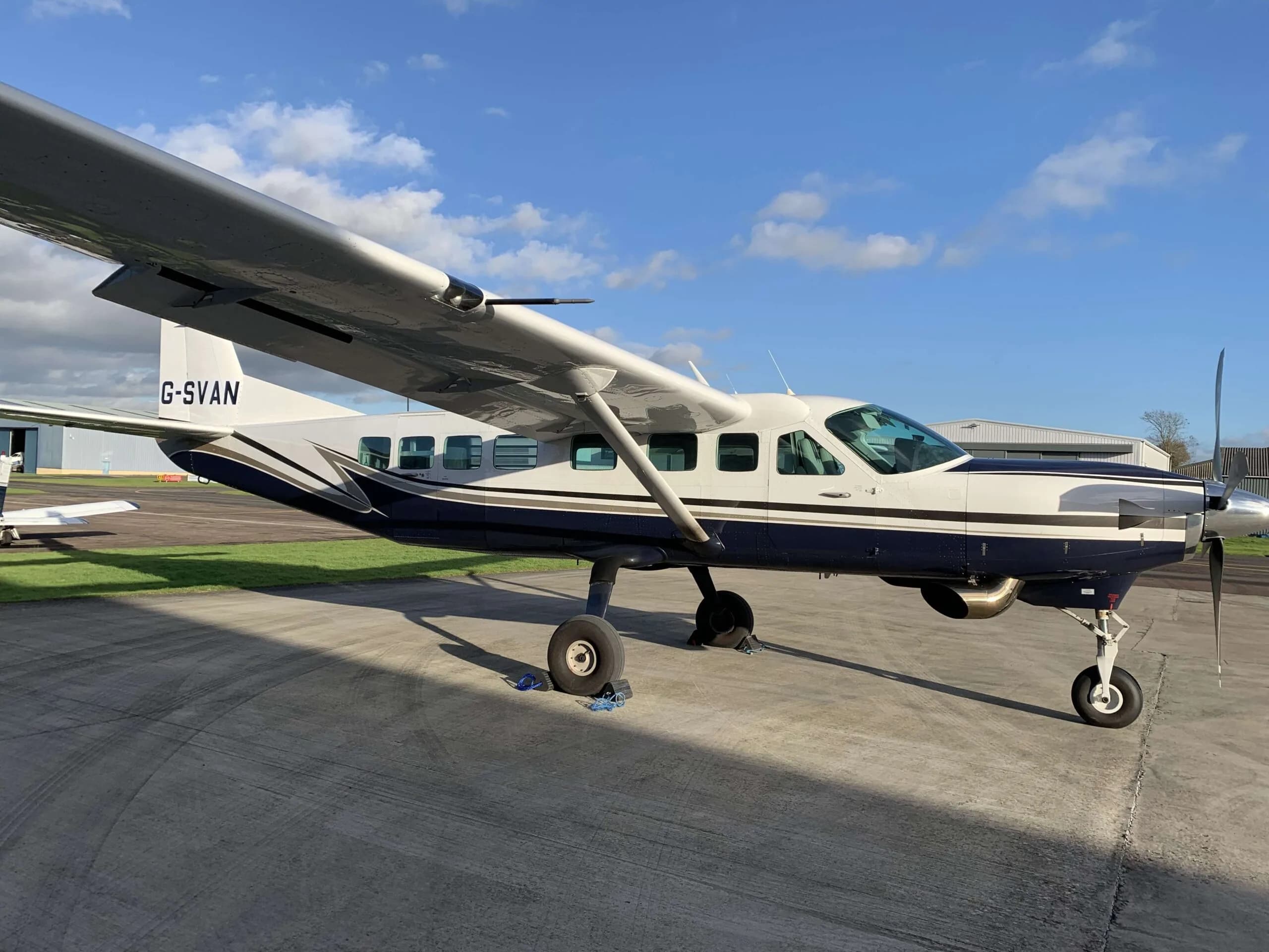 A Cessna Caravan aircraft with a blue and white paint scheme parked on the tarmac.