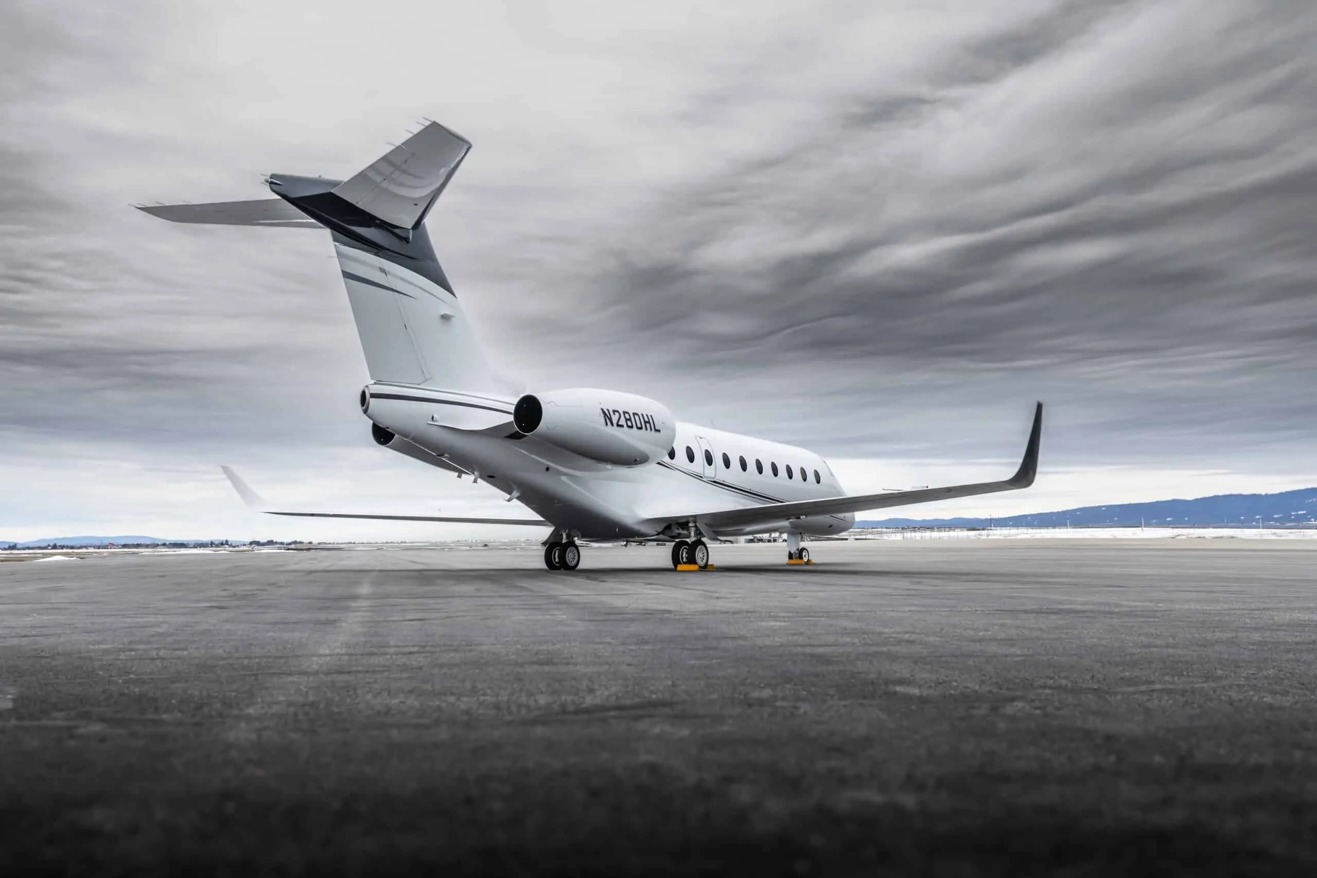 A rear three-quarter view of the white Gulfstream G550 (or similar large business jet) N280HL on a tarmac.