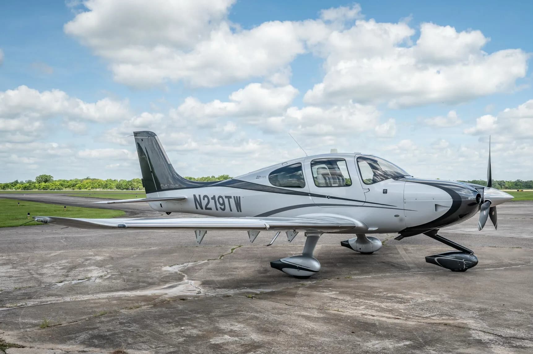 A side view of the Cirrus SR22T GTS Platinum aircraft N219TW parked on a concrete apron.